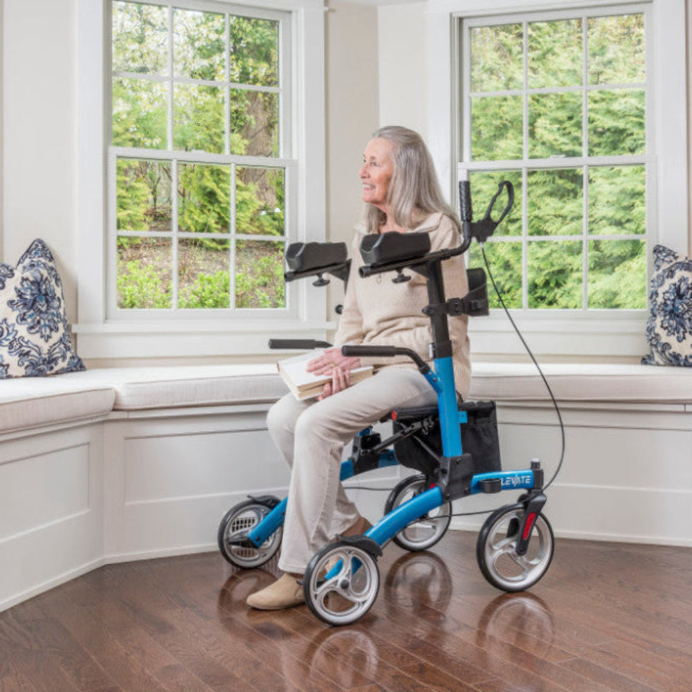 Woman seated on a Blue Drive Medical Elevate upright walker indoors